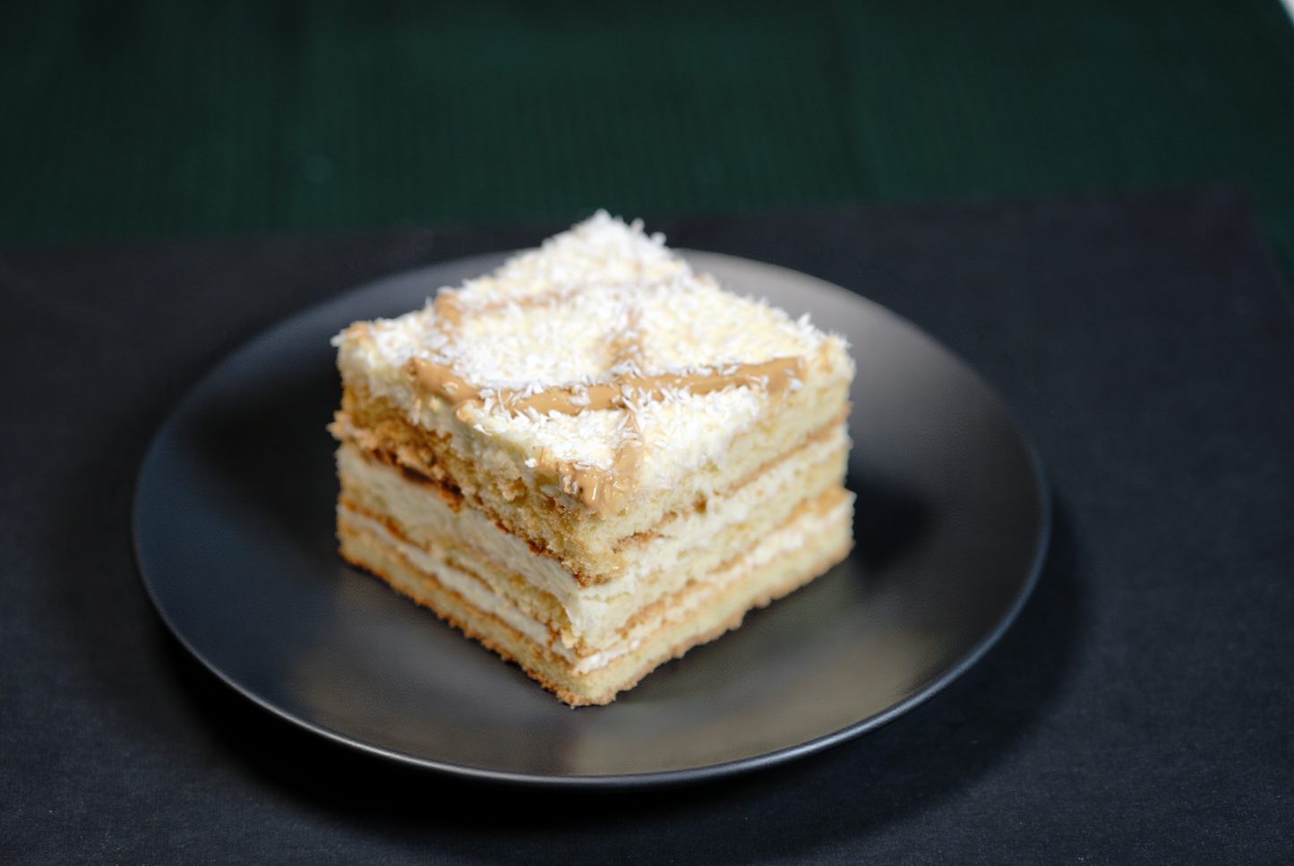 Handmade raffaello cake with sponge layers and cream layers sprinkled with coconut flakes
